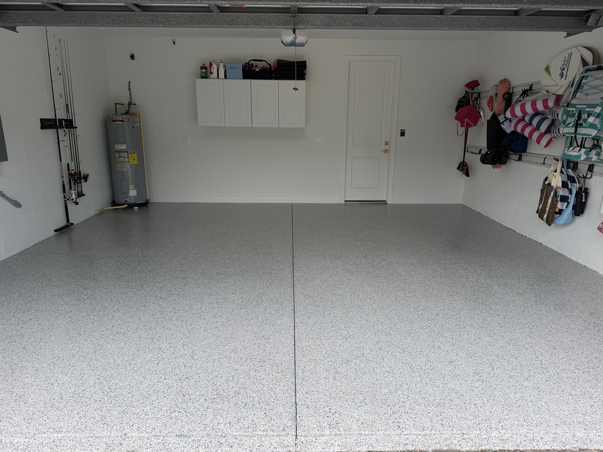 Light gray flake garage floor with beach chairs, fishing rods and coolers stored along the wall
