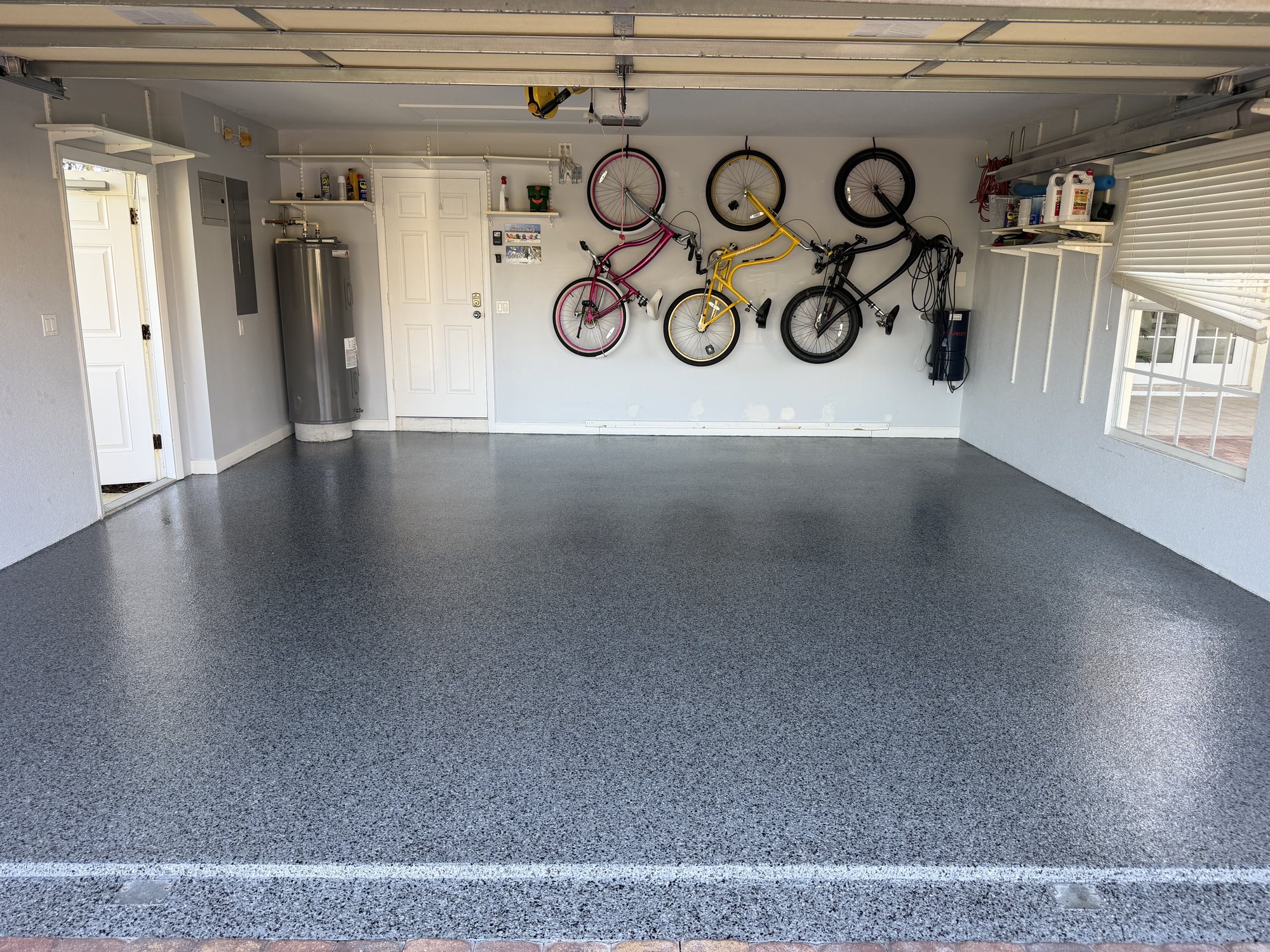 Blue-gray flake garage floor with bicycles hung along the wall and storage shelving