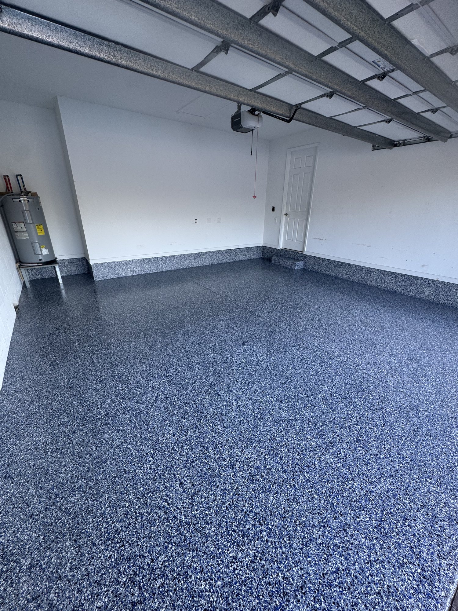 Blue and gray flake garage floor carried up the wall as a coved base, full-flake system