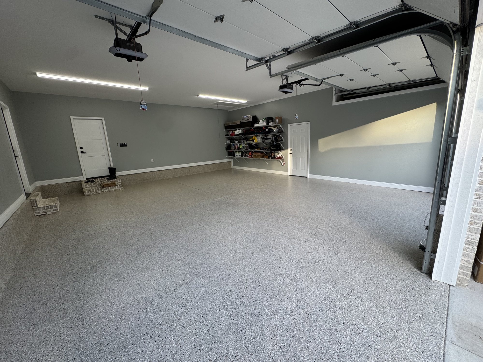 Wide gray flake floor in a large multi-car garage with sage green walls and a coved flake base