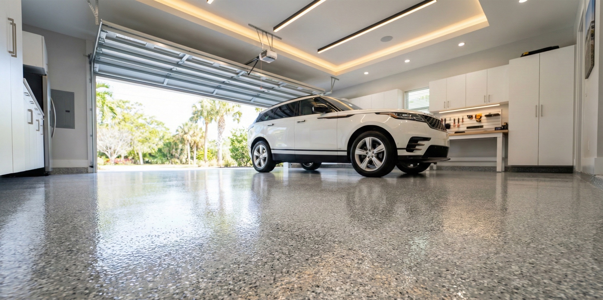Speckled gray flake garage floor with a white Range Rover in the bay and built-in white cabinetry along the wall