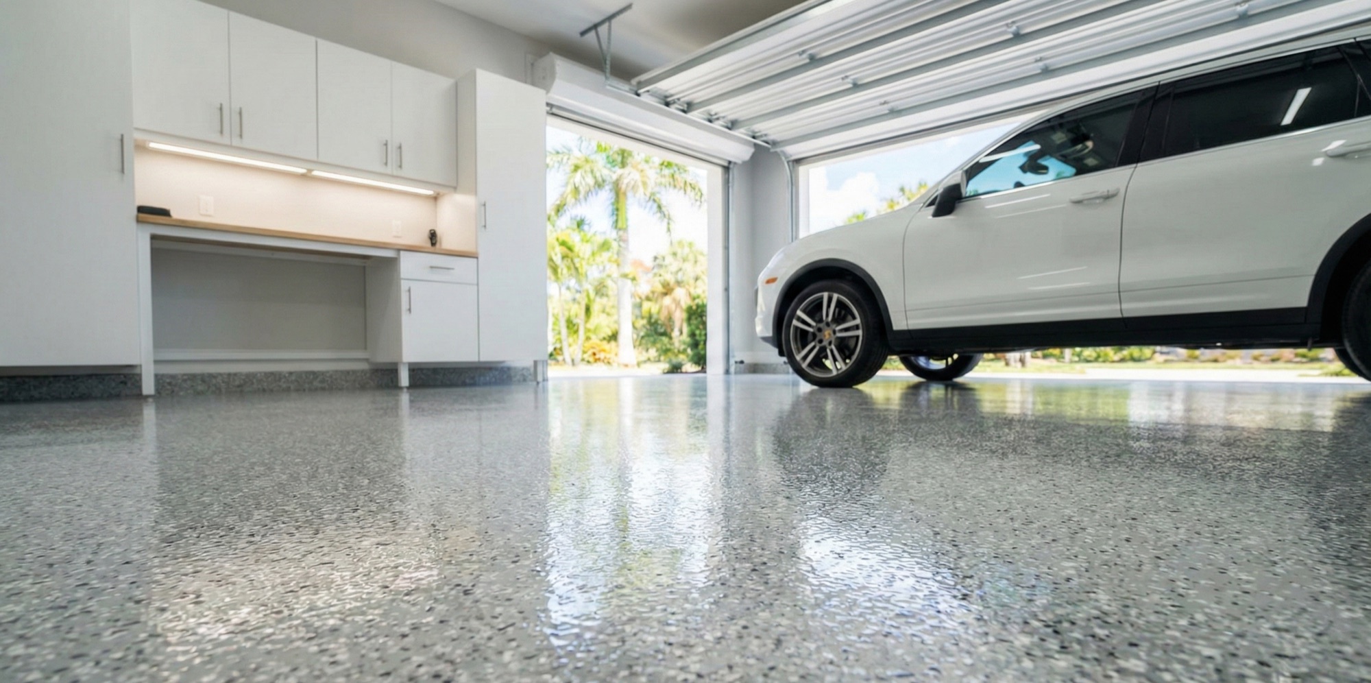Gray flake garage floor with a white SUV parked at the open door and a lit workbench along the back wall