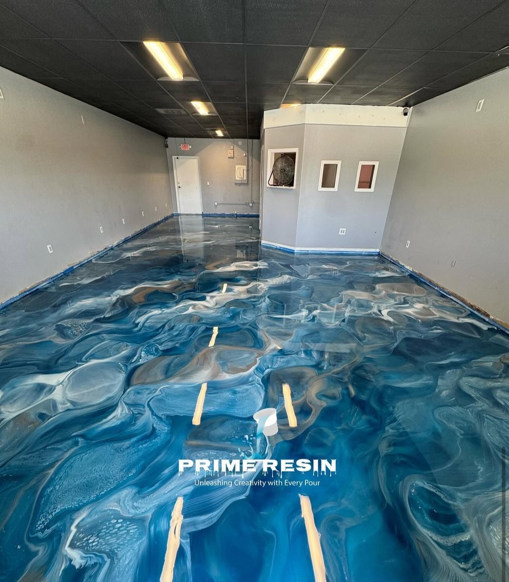 Blue and white metallic epoxy poured wall to wall across a commercial suite, blue masking tape still at the perimeter